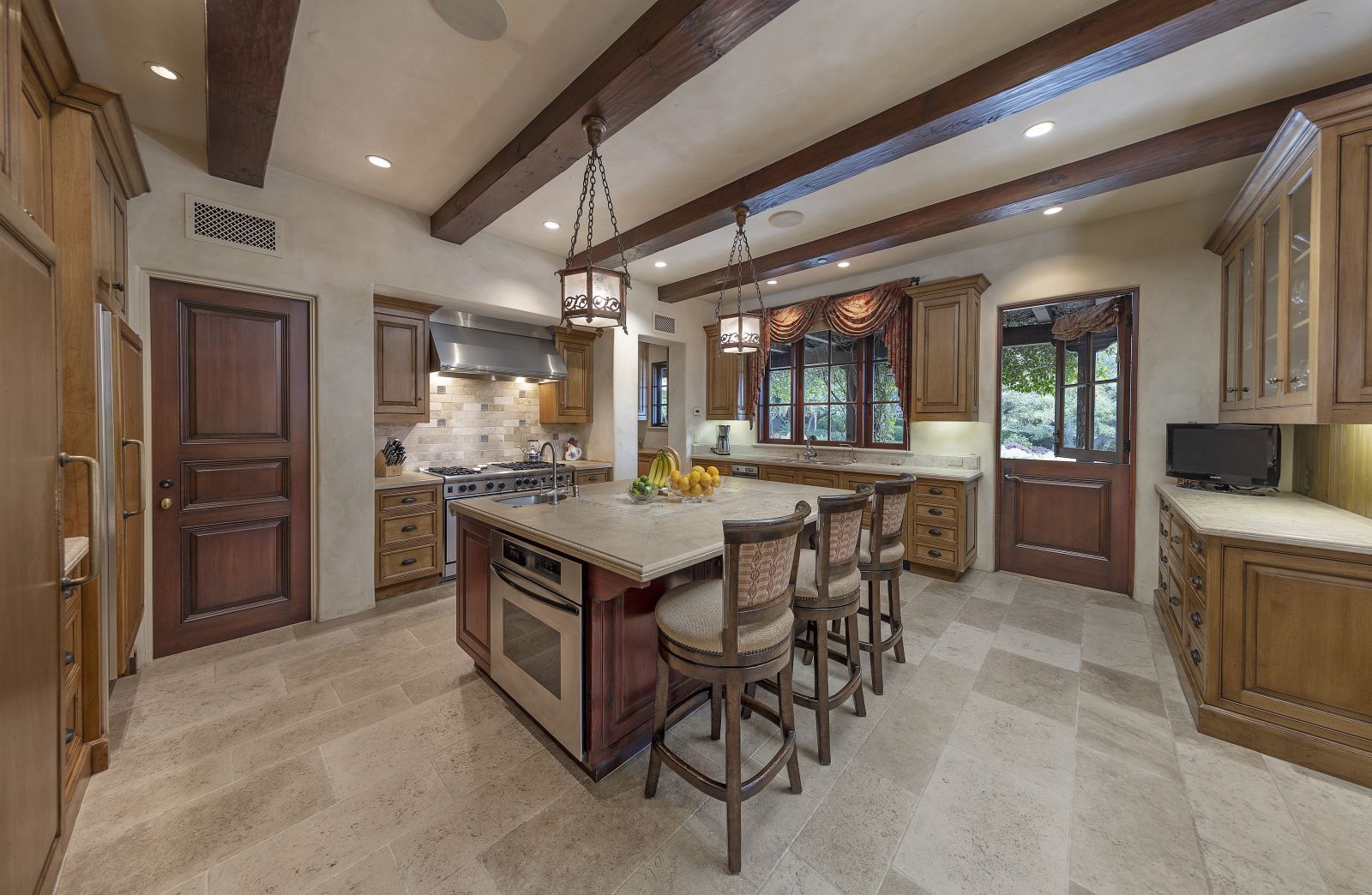 A luxury kitchen with wood beams on the ceiling, a versatile center island and top of the line appliances.